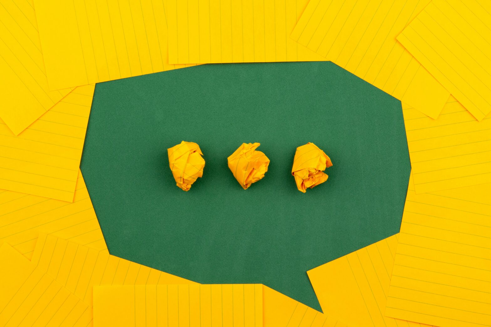Verbal Behavioural Intelligence, illustrated by orange sheets of paper lie on a green school board and form a chat bubble with three crumpled papers. Photo by Volodymyr Hryshchenko on Unsplash